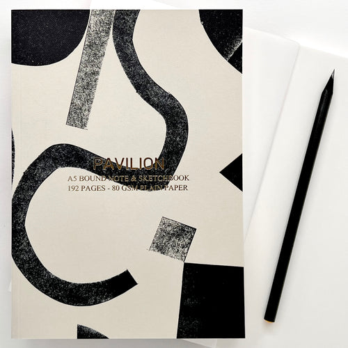 Bass A5 notebook featuring a monochrome abstract cover with gold foil details, shown with a black pencil.
