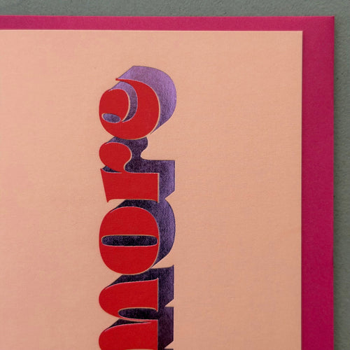 Close-up of the red lettering and metallic purple foil detail on the peach Amore card.