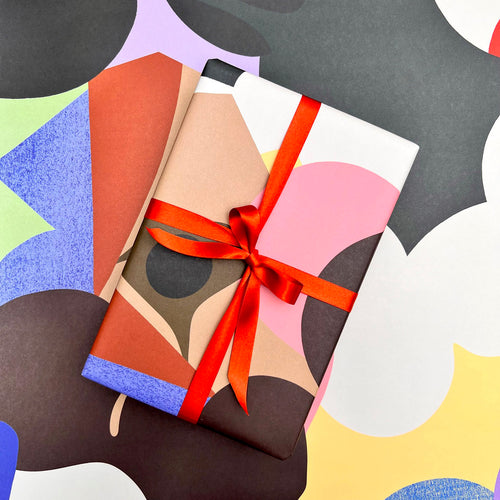 Assemblage gift wrap styled with coordinating abstract wrapping paper and red ribbon