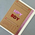 Angled view of the Birthday Ticket greeting card with a cream envelope, showcasing the modern ticket design and colourful foil accents.