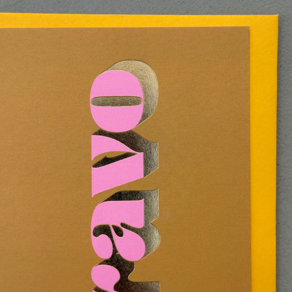 Close-up of the pink lettering and gold foil detail on the ochre Bravo card.