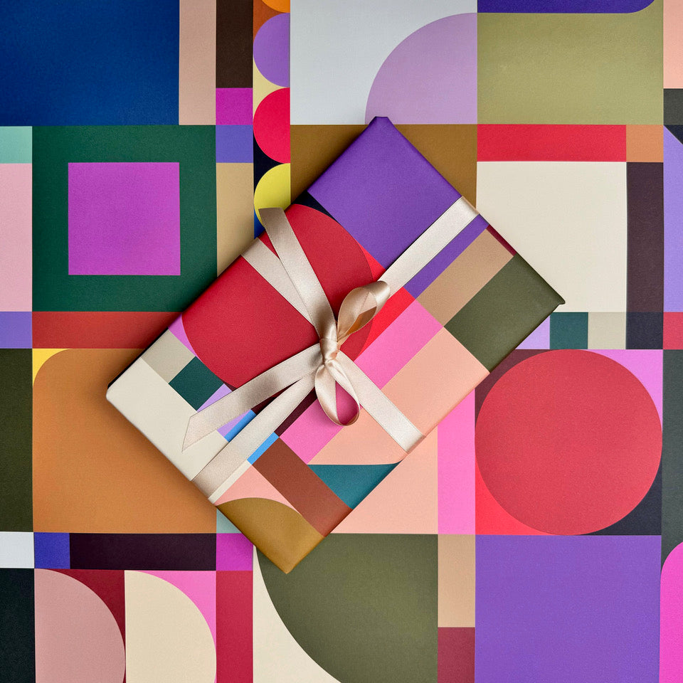 Broadcast wrapping paper with wrapped gift styled against the geometric pattern