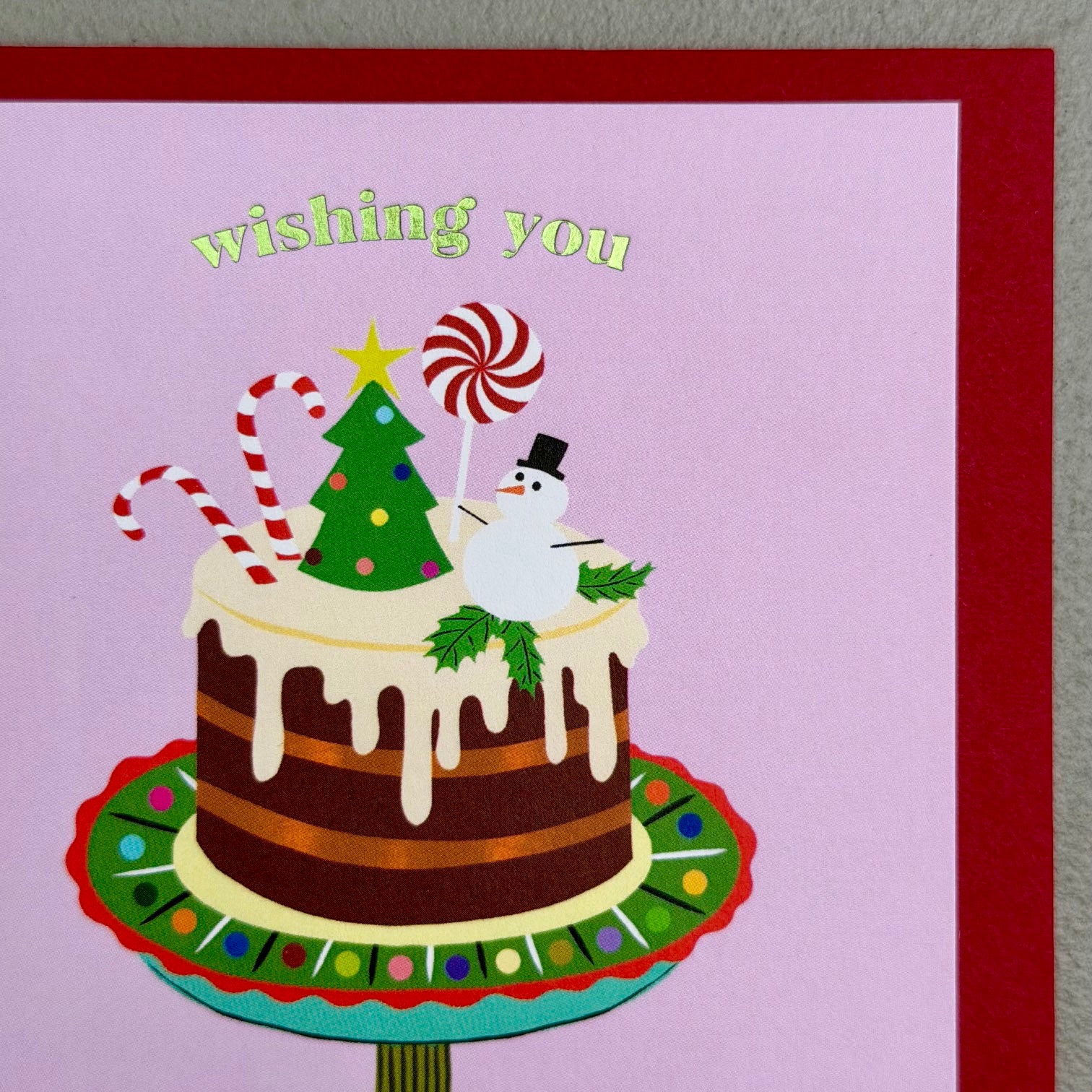 Close-up of Cake Christmas card showing festive cake, snowman, candy canes and foil lettering
3