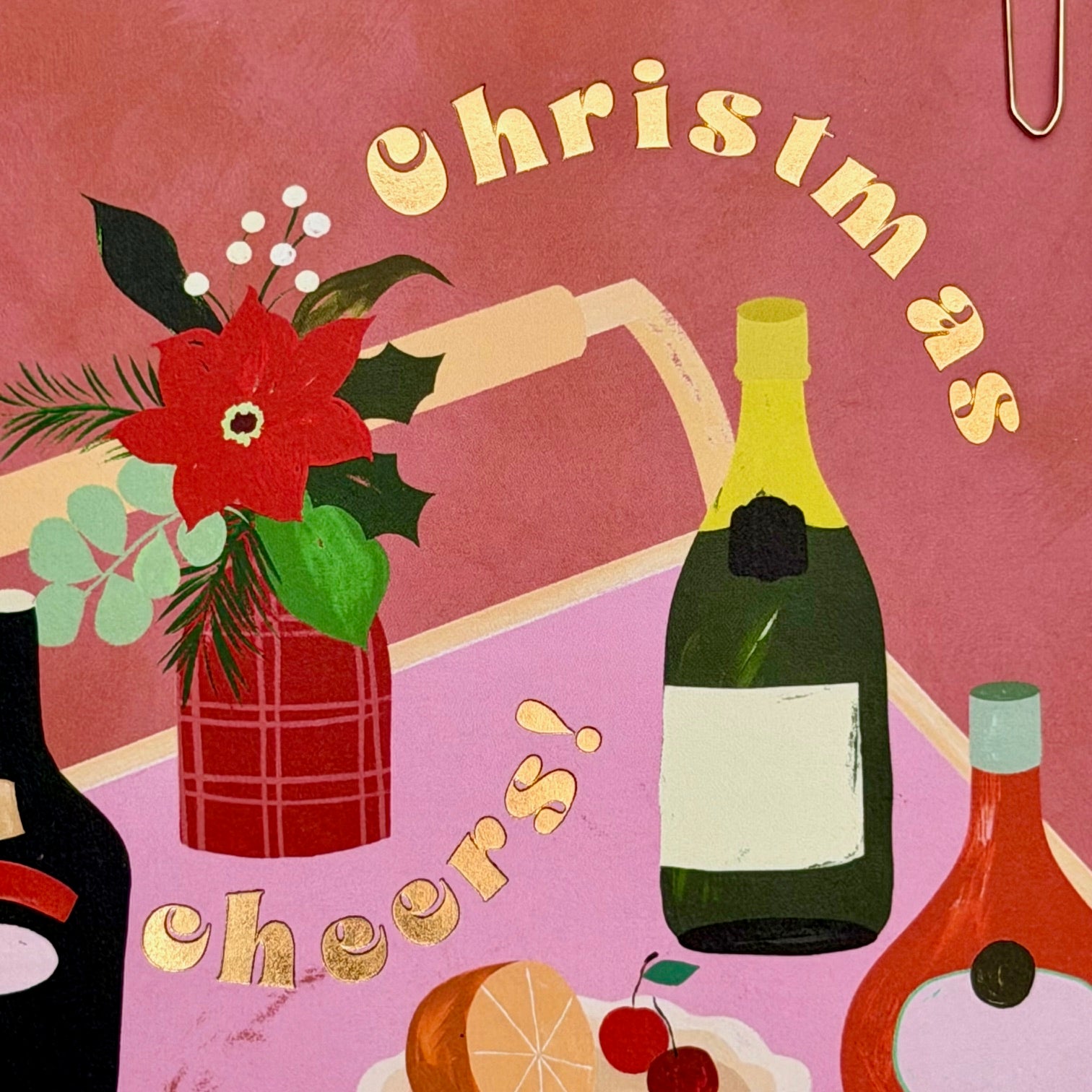Close-up of the gold foiled Christmas Cheers lettering and illustrated drinks scene