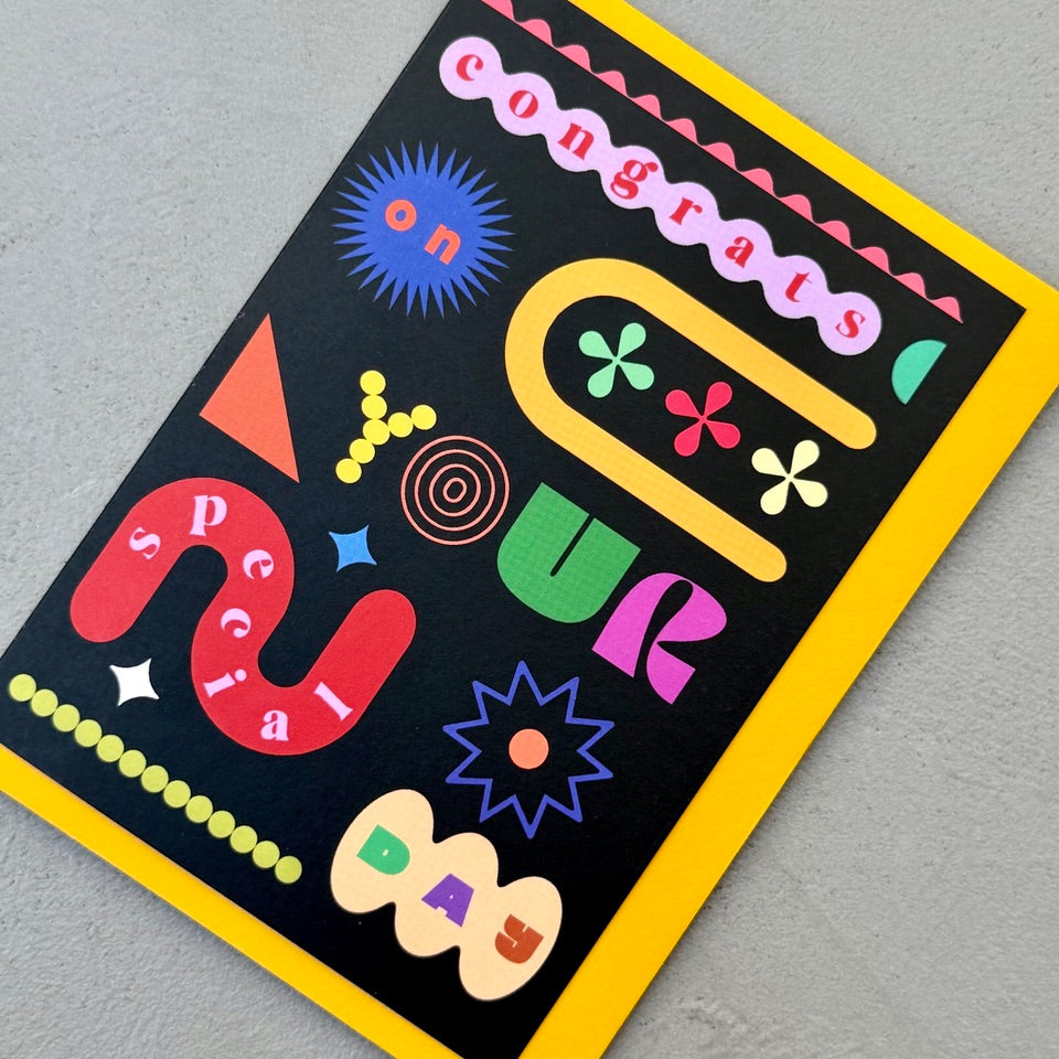 Angled view of the Congrats On Your Special Day greeting card on a mustard yellow envelope.