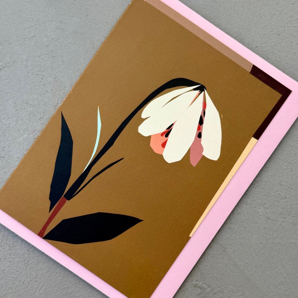 Angled view of the illustrated drooping bloom greeting card on a pink envelope.

