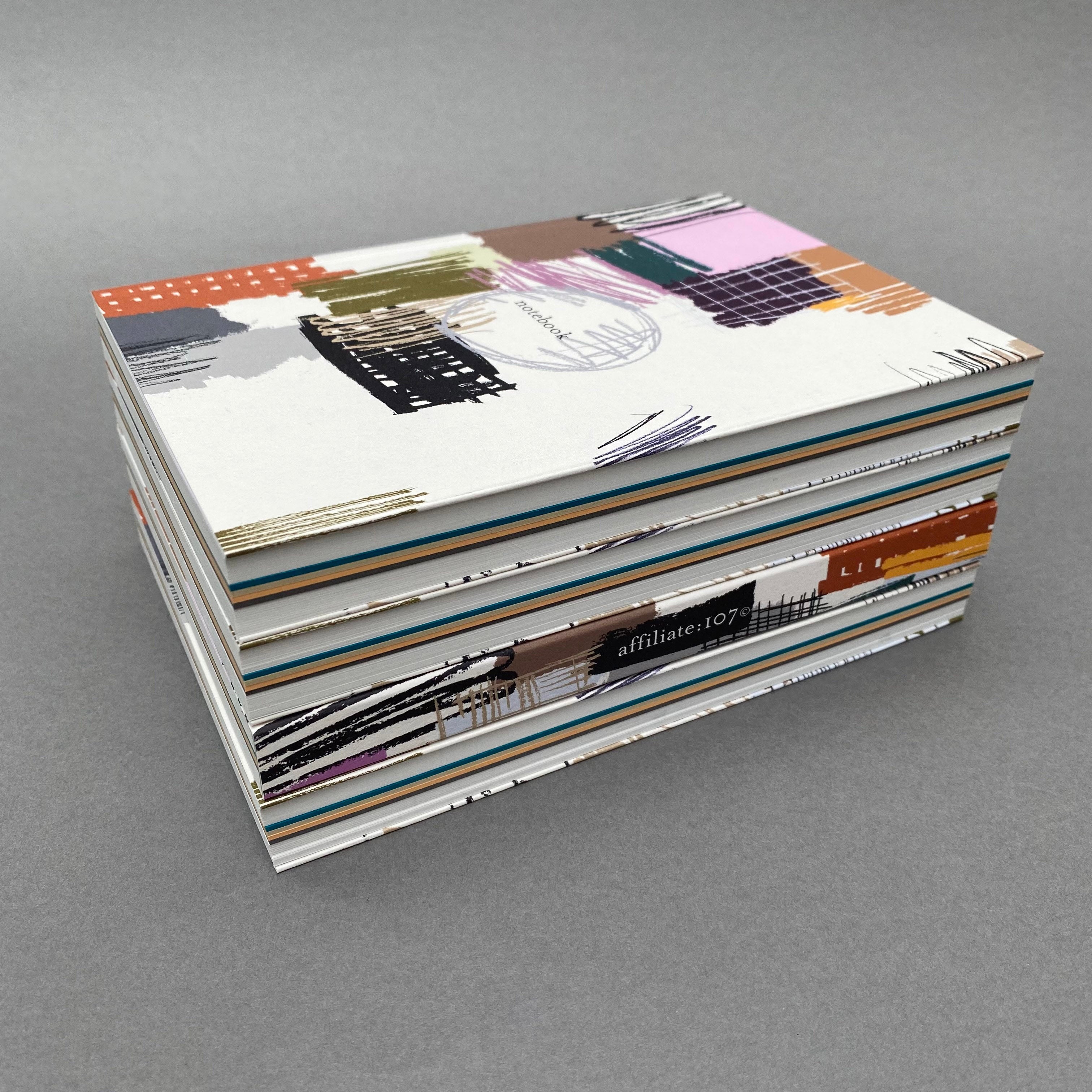 Stack of Etch Notebooks showing colourful page sections and extended covers