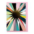 Greeting card featuring a gold foil starburst with soft pastel and jewel-toned rays on a pale pink envelope.