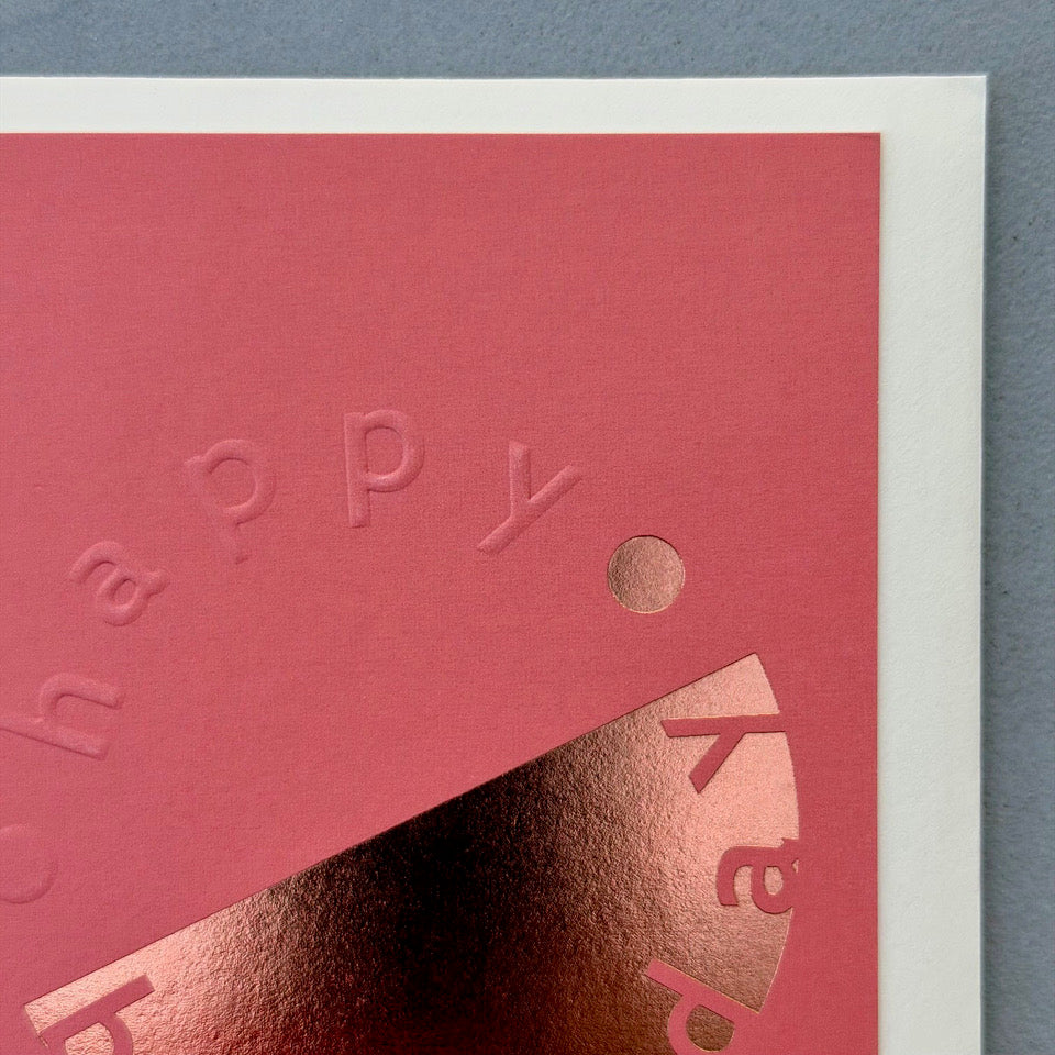 Close-up of the embossed lettering and copper foil detail on the coral pink Happy Birthday card.