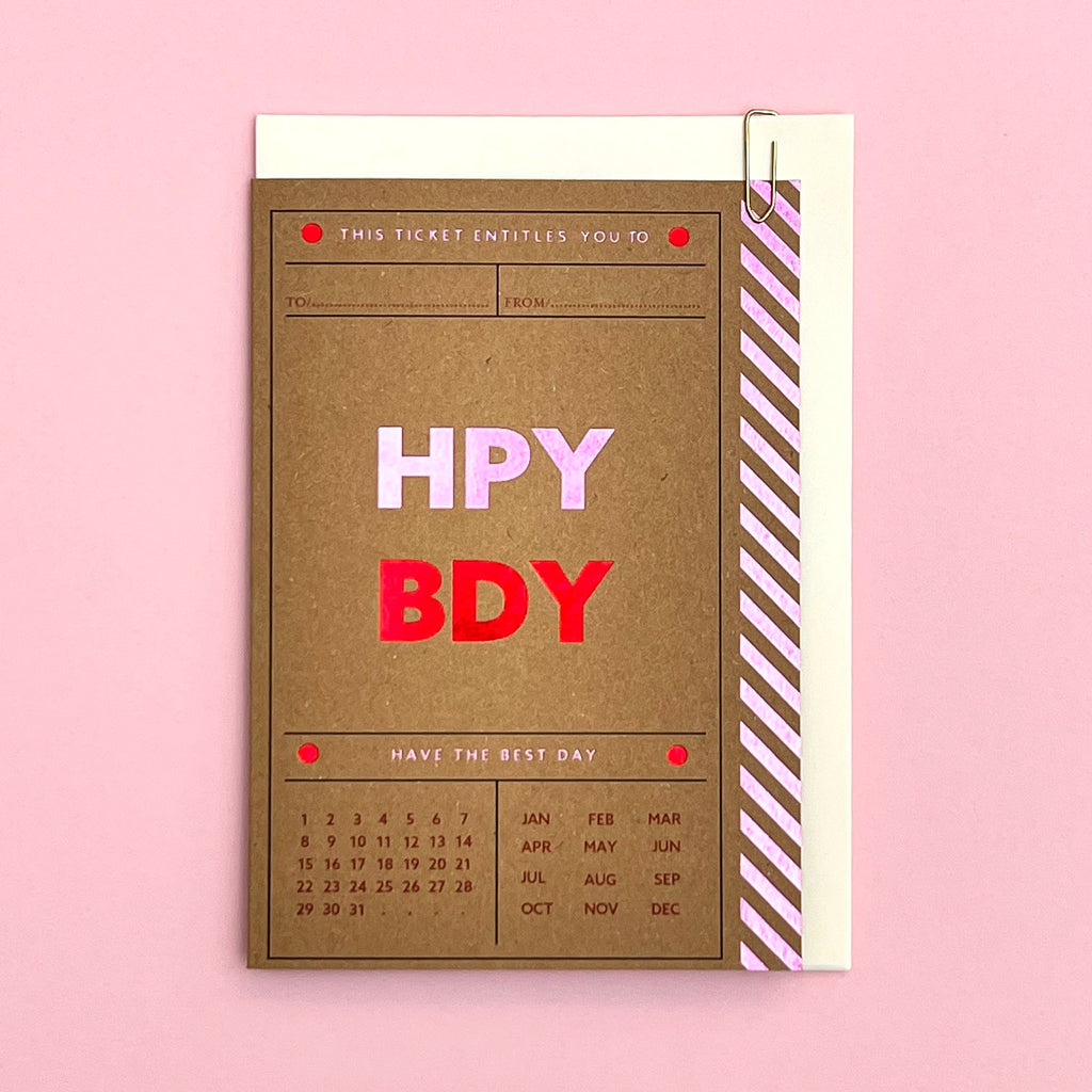 Happy Birthday ticket-style card with cream envelope on a pink background