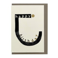 Minimalist Happy Birthday card featuring bold black typography, gold foil accents and a contemporary graphic design, paired with a warm grey envelope.
