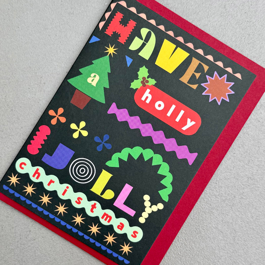 Angled view of Have A Holly Jolly Christmas card by PAVILION with red envelope