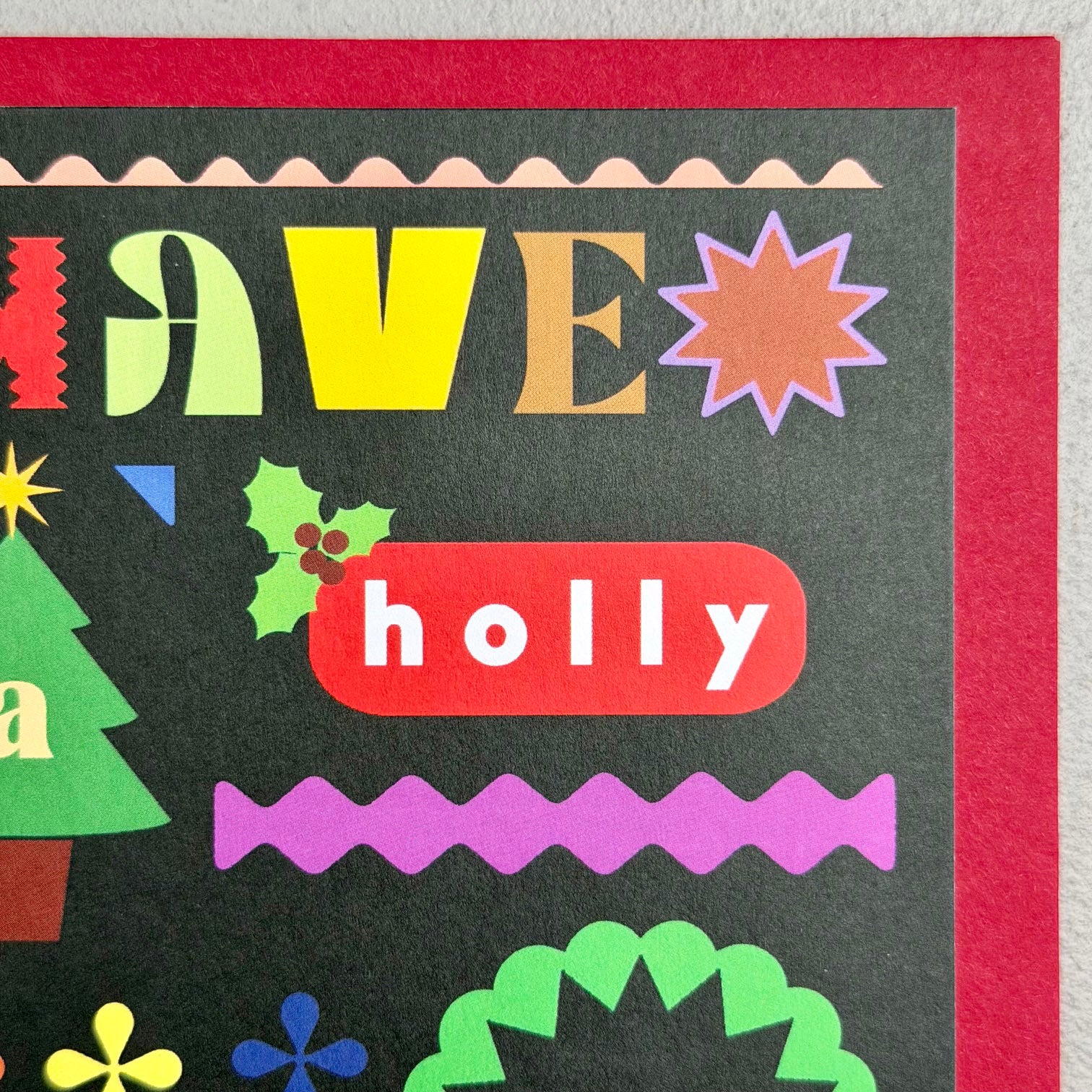 Close-up of Have A Holly Jolly Christmas card showing playful typography, holly and graphic festive details