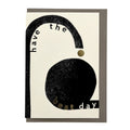 Modern typographic greeting card with bold black abstract shapes, gold foil details and the message "Have the Best Day", paired with a warm grey envelope.