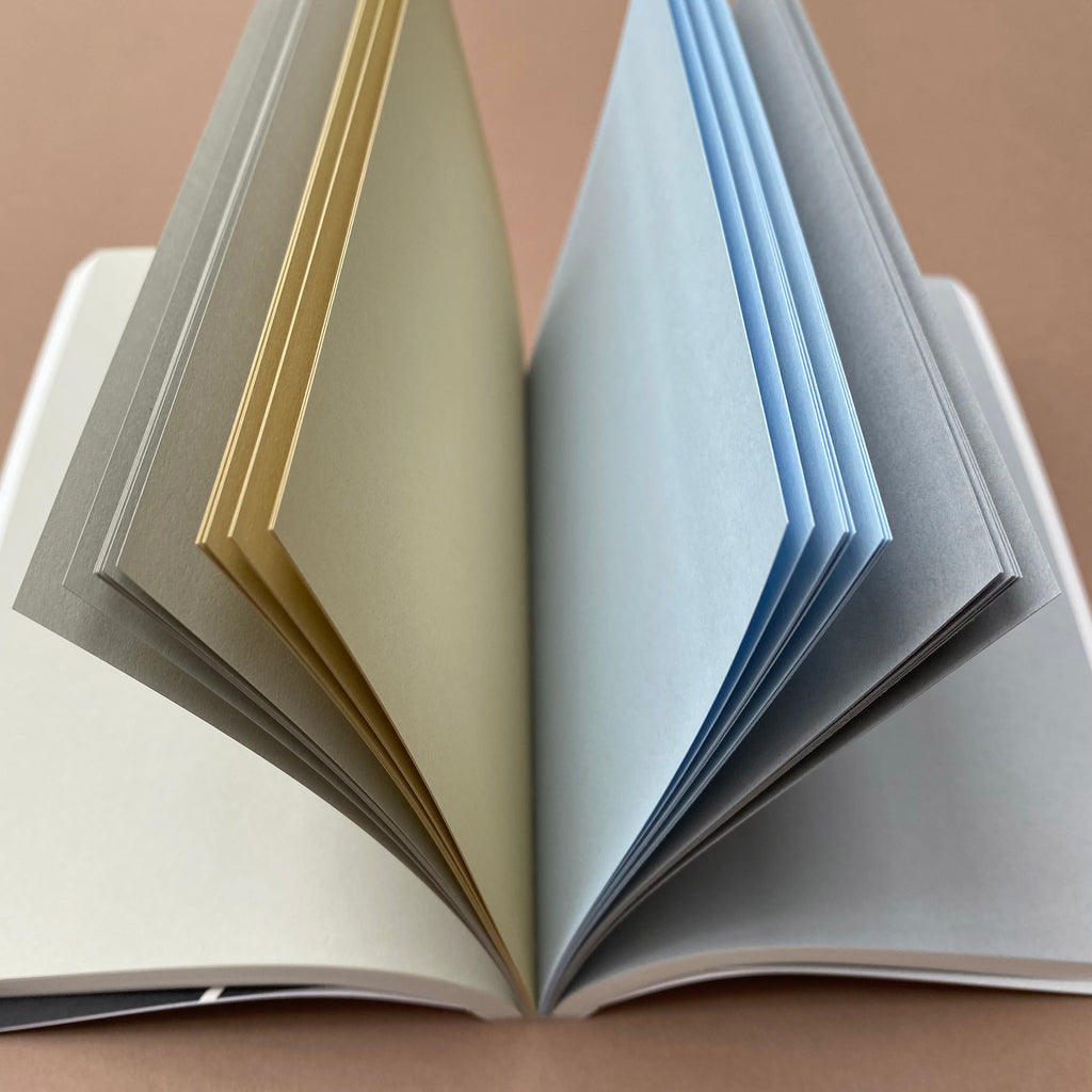 Ink Notebook open showing neutral, yellow, blue and grey coloured Go-To pages