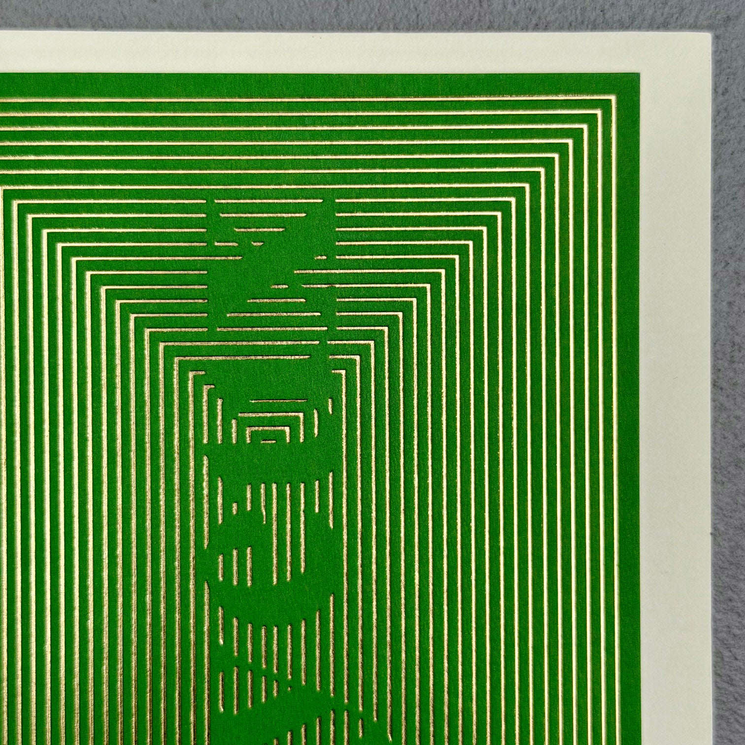 Close-up of Joyeux Christmas card showing intricate gold foil lines with gaps forming the word Joyeux
