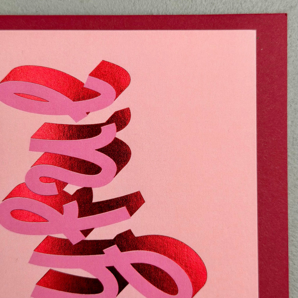 Close-up of Joyful Christmas card showing sculptural pink lettering and red foil details