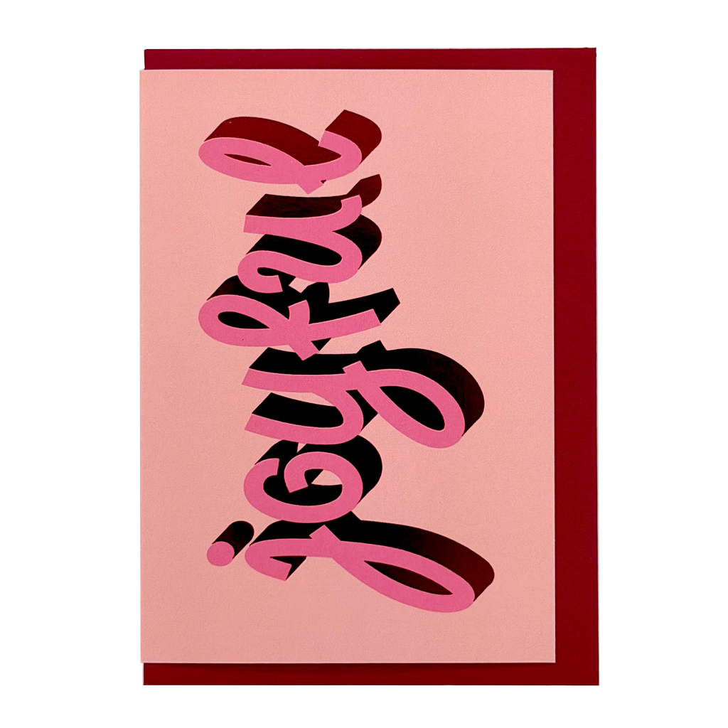 Front view of Joyful Christmas card by PAVILION with pink sculptural lettering on a pale pink background and crimson envelope