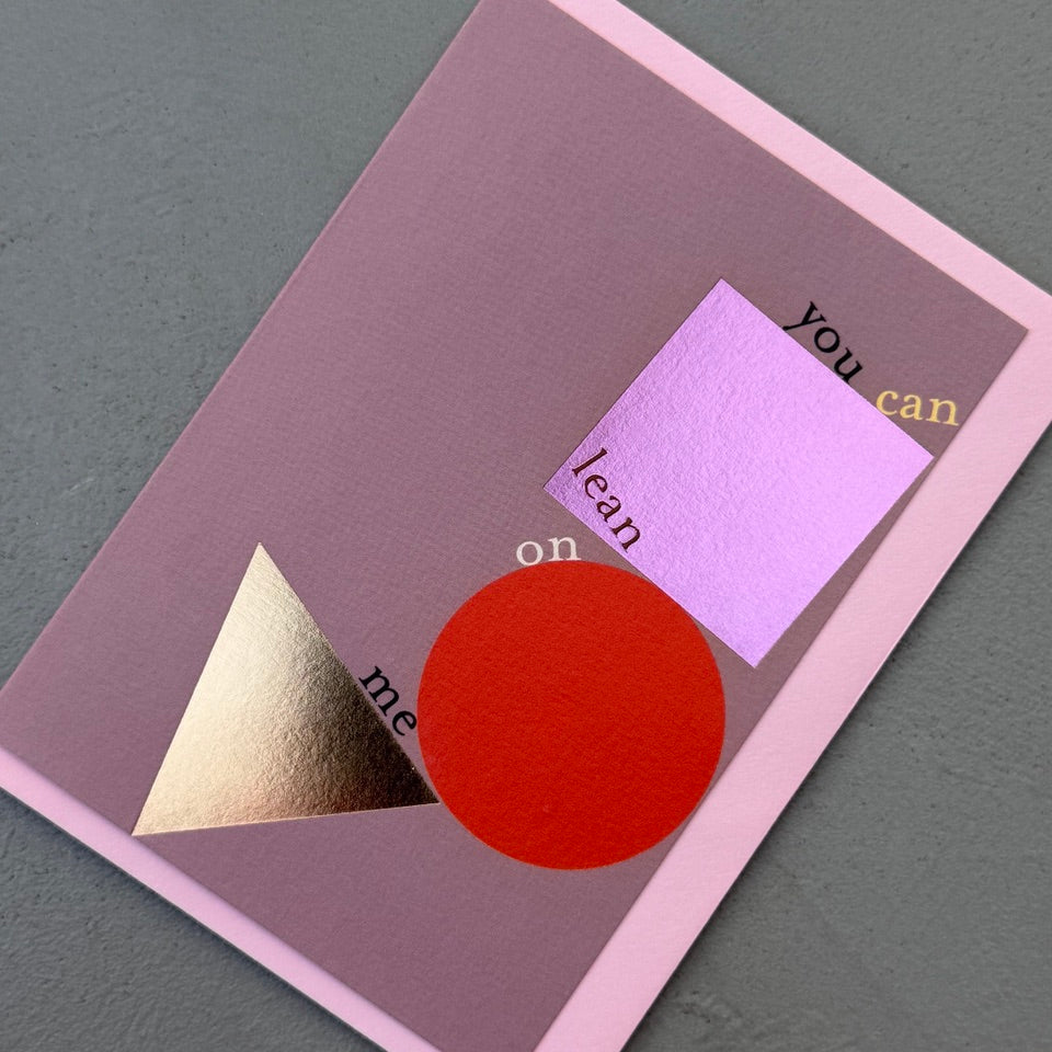 Angled view of the Lean On Me greeting card with a soft pink envelope, showcasing the contemporary geometric design and reflective foil accents.