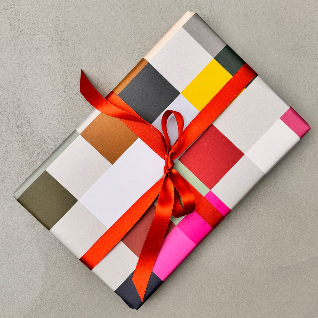 Wrapped gift in Madras wrapping paper with red ribbon