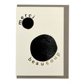 Minimalist thank you card featuring bold black abstract circles, gold foil typography reading "Merci Beaucoup", and a warm grey envelope.
