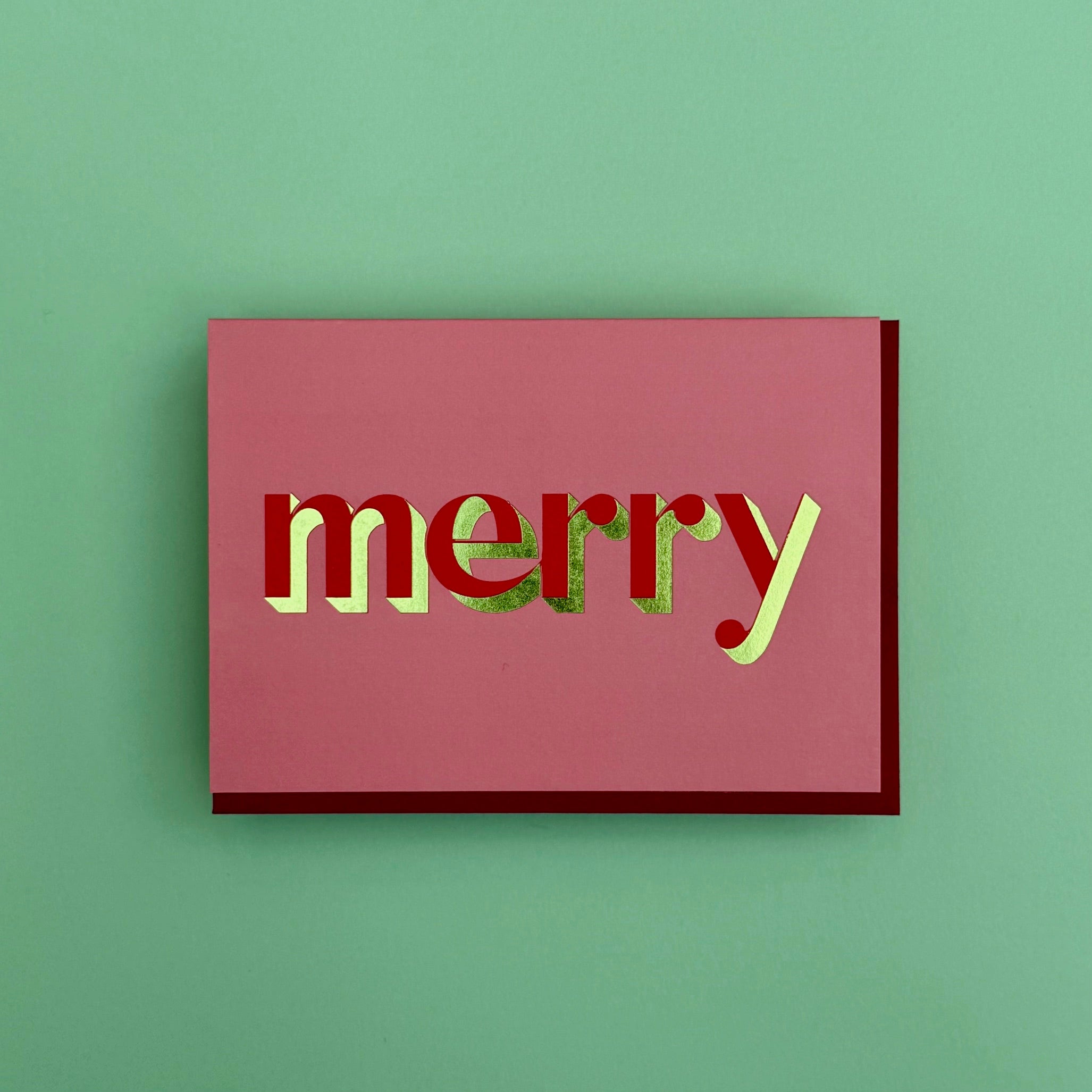 Merry Christmas card standing against a green background