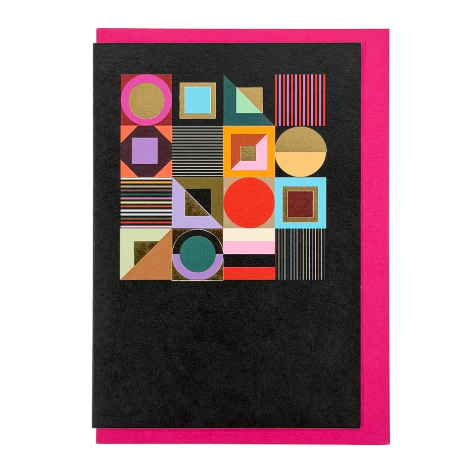 Contemporary geometric greeting card featuring colourful abstract shapes with gold foil details on a black background, paired with a bright pink envelope.