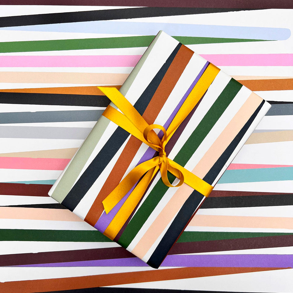Mondo wrapping paper with wrapped gift styled against the colourful striped pattern