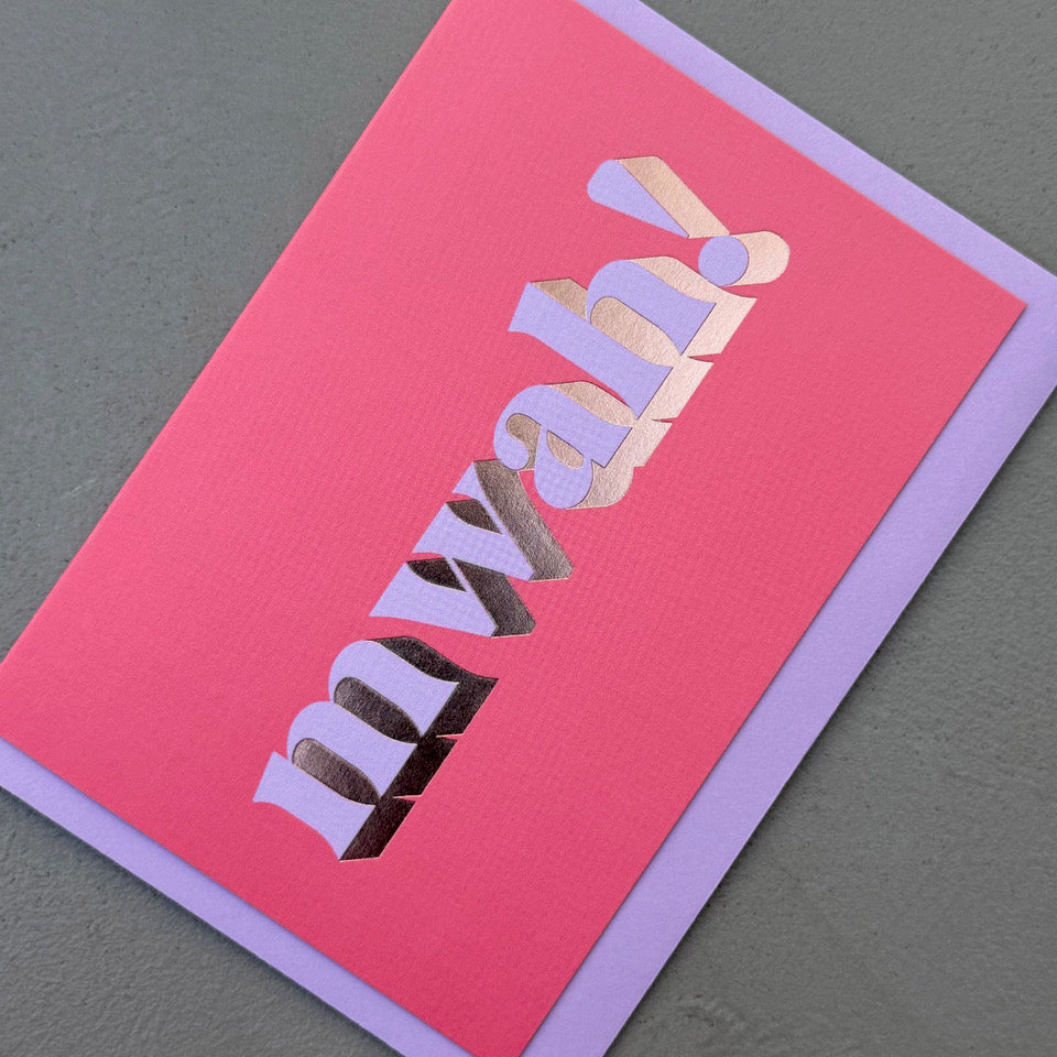 Angled view of the bright pink Mwah! card showing the lilac lettering and reflective gold foil.