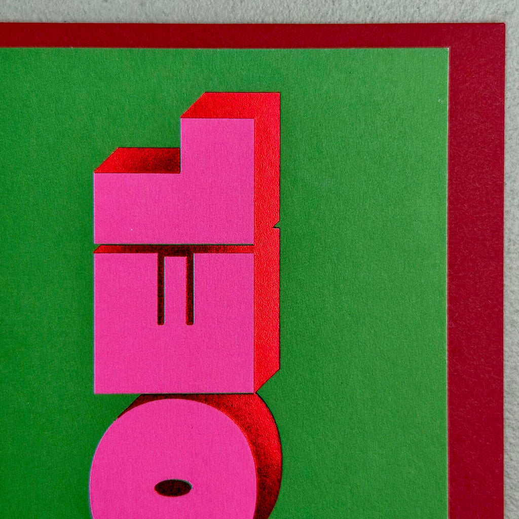 Close-up of Noel Christmas card showing bold pink 3D lettering and red foil details