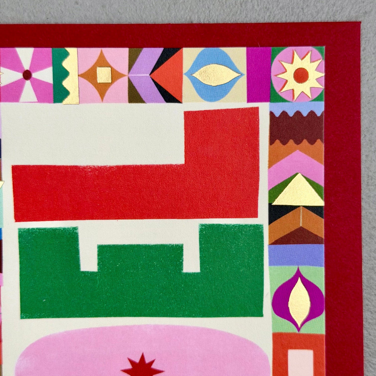 Close-up of NOEL Christmas card showing graphic letterforms, patterned border and gold foil details
