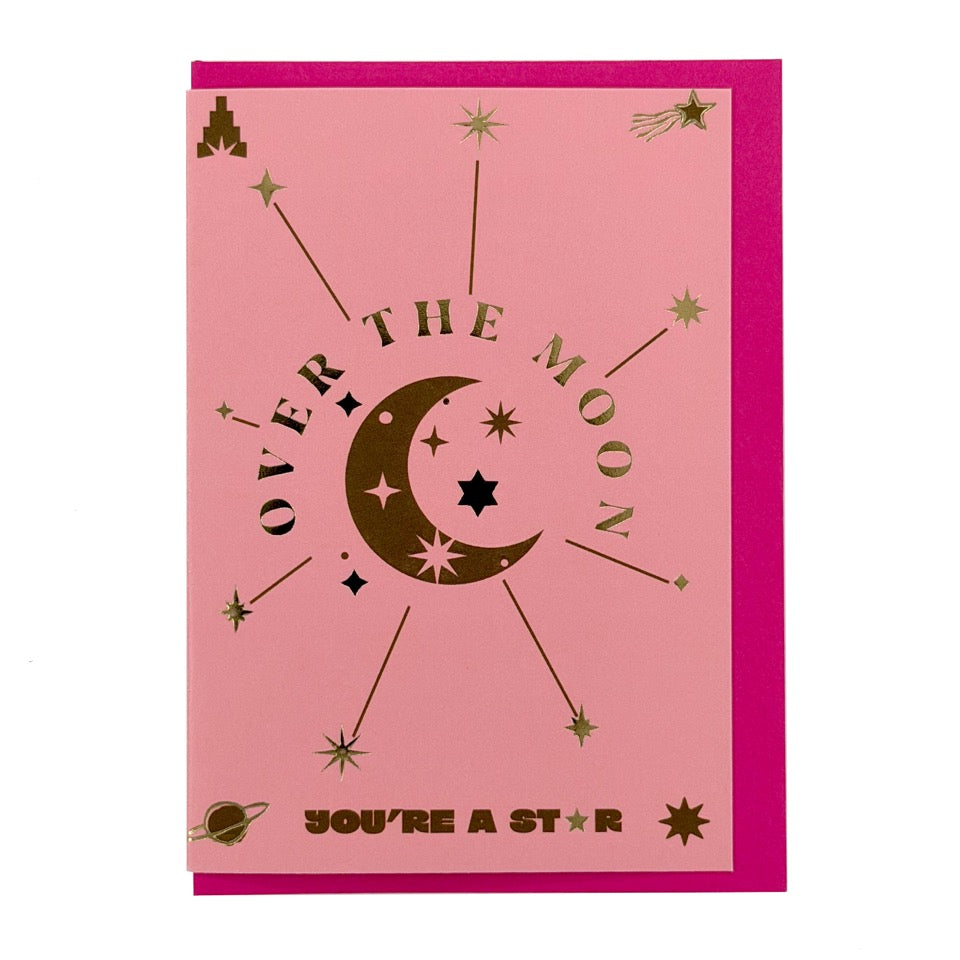 Foil-embellished greeting card featuring a crescent moon, stars and the message "Over the Moon You're a Star", paired with a bright pink envelope.