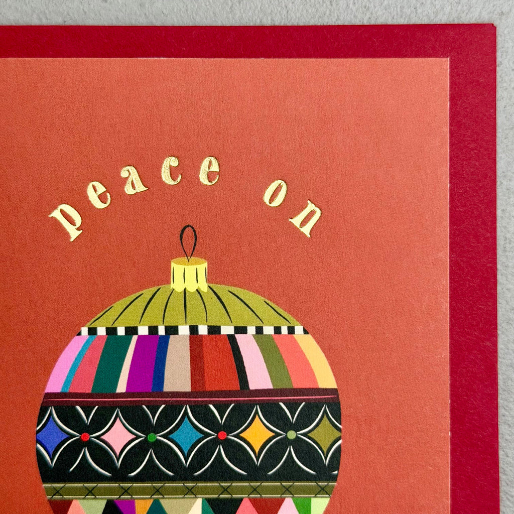 Close-up of Peace Bauble Christmas card showing patterned bauble and gold foil “peace on earth” lettering