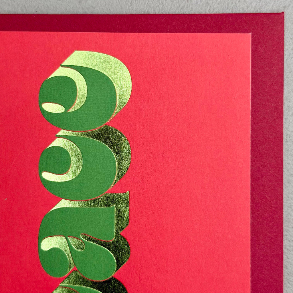 Close-up of Peace Christmas card showing sculptural green lettering and gold foil details