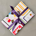 Wrapped gift in Scrapbook wrapping paper with purple ribbon