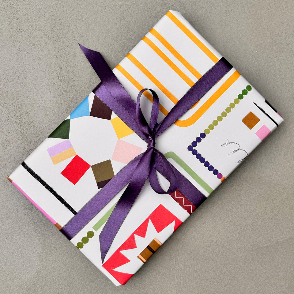 Wrapped gift in Scrapbook wrapping paper with purple ribbon