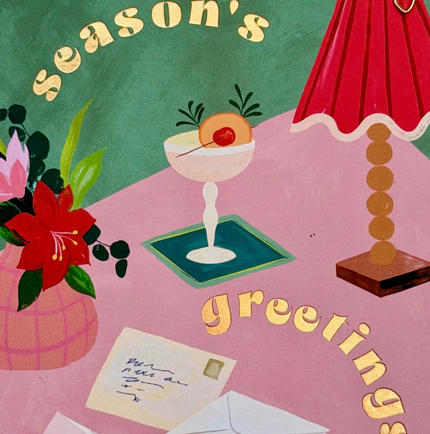 Close-up of the gold foiled Season's Greetings lettering and illustrated festive tabletop