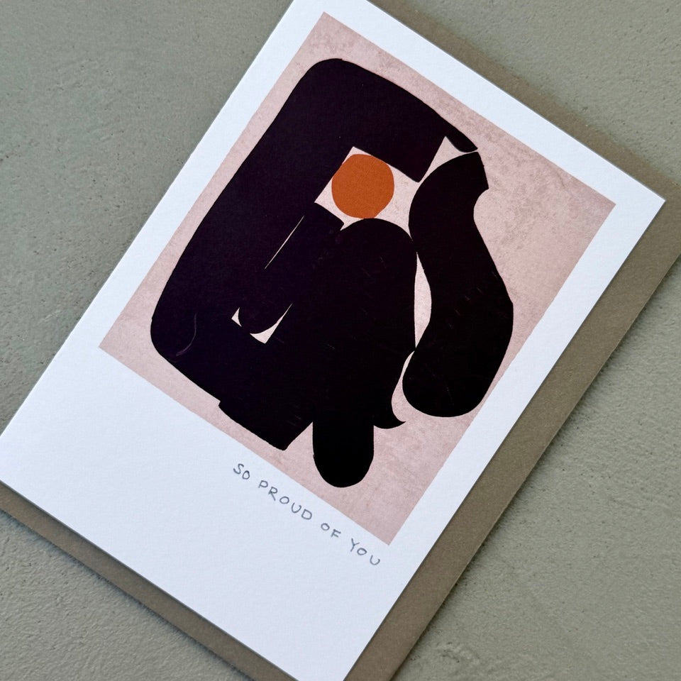 Angled view of the So Proud of You greeting card with abstract artwork and a grey envelope.