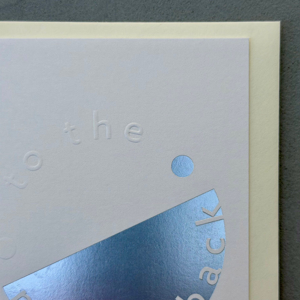 Close-up of the embossed lettering and silver foil detail on the pale grey To the Moon & Back card.