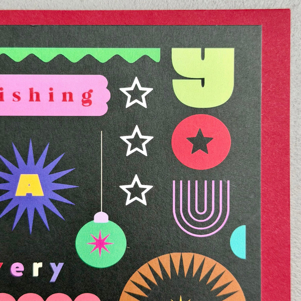 Close-up of Wishing You A Very Merry Christmas card showing stars, bauble and colourful graphic details
