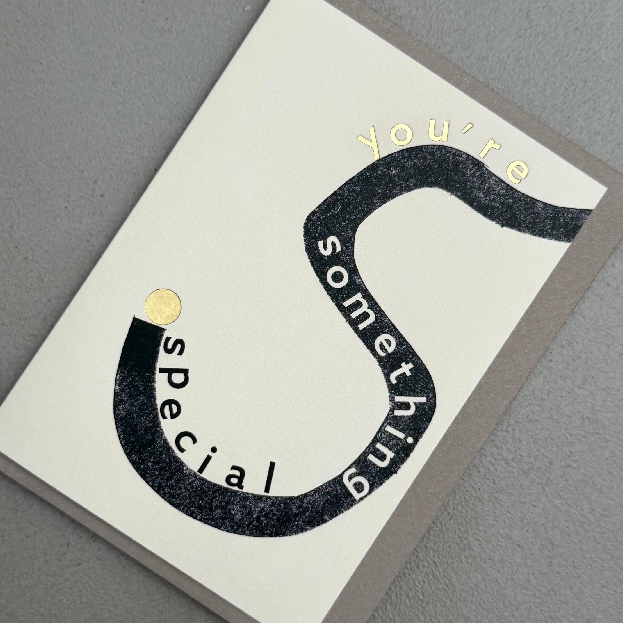 Angled view of You’re Something Special card by PAVILION with bold black curved typography, gold foil details and grey envelope